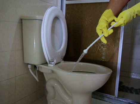 salvador, bahia, brazil - february 21, 2021: person wearing a rubber glove while cleaning a bathroom toilet in a residence in the city of Salvador.