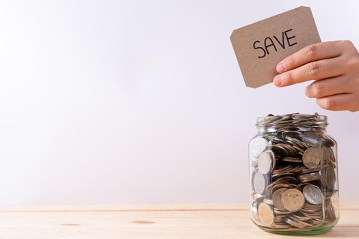 Jar full of coins with travel word paper on wooden table isolated grey background. Saving money and investment concept.