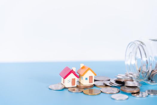 House and coins in jar isolated grey background. Property investment and house mortgage financial concept.