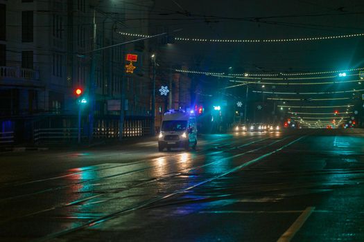 Tula, Russia - December 31, 2020: Ambulance car moving toward camera on empty night street in city.