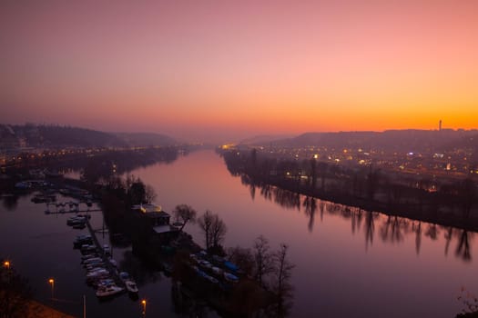 Small dock, boats and Vltava River in Prague, Czech Republic, viewed from the Vysehrad fort in the dramatic sunset.