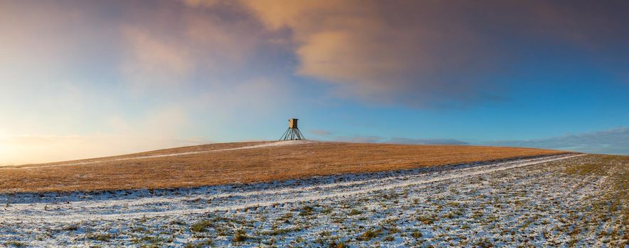 Lookout tower for hunting on the hill at sunrise. Winter scenery.