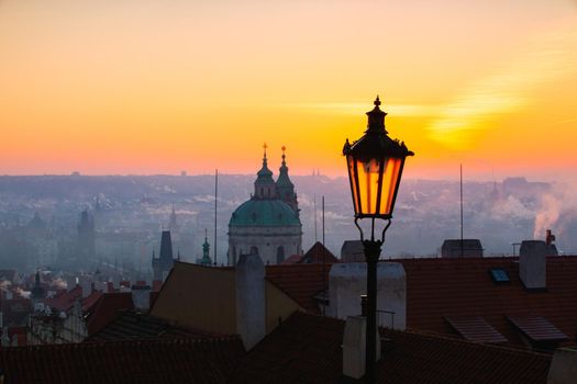 Sunrise behind an old street lamp over Lesser Town, Prague, Czech Republic. Lesser Town is a hillside area with views across the Vltava river to the old town.