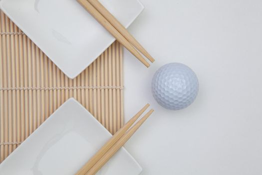 Top View Of White Empty Sushi Plates With Bamboo Chopsticks and Golf Ball. Golf  Design