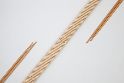 Bamboo mat with chopsticks for sushi on the white table. Food Design