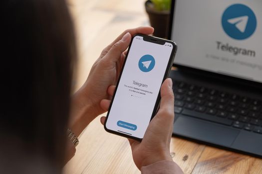 CHIANG MAI, THAILAND, MAR 21, 2021 : Woman hand holding iPhone X with social networking service Telegram on the screen. iPhone 10 was created and developed by the Apple inc.