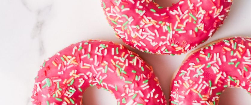 Bakery, branding and cafe concept - Frosted sprinkled donuts, sweet pastry dessert on marble table background, doughnuts as tasty snack, top view food brand flat lay for blog, menu or cookbook design