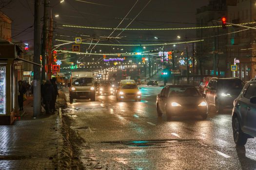 Tula, Russia - December 20, 2020: Night automobile traffic on wide city street - close-up telephoto shot.