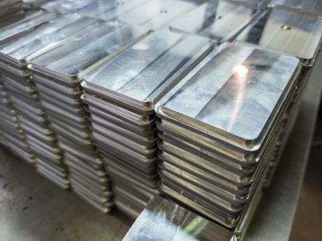stacks of shiny metal tiles after cnc surface milling - close-up with selective focus