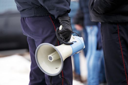 police officer holding loudspeaker megaphone at daylight, close-up with selective focus