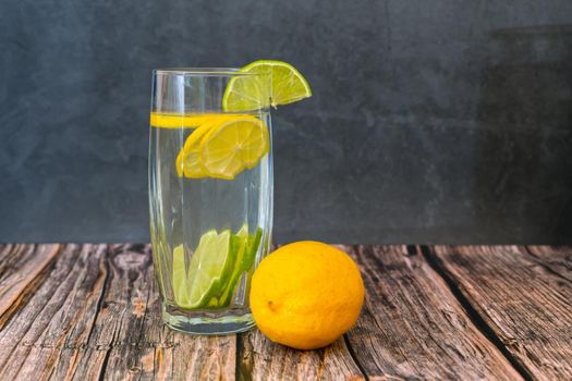 Glass of lemon and lime refreshing drink on dark background