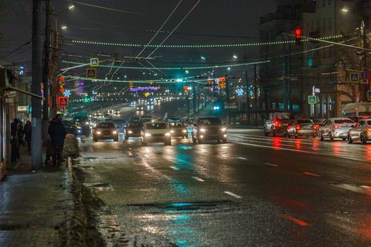 Tula, Russia - December 20, 2020: Night automobile traffic on wide city street - close-up telephoto shot.