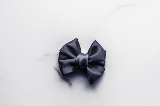 Holiday gift, decoration and sale promotion concept - Black silk ribbon and bow on marble background, flatlay