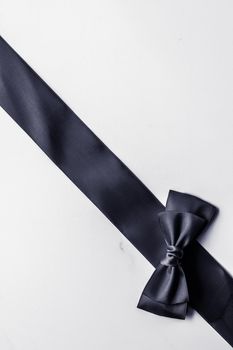 Holiday gift, decoration and sale promotion concept - Black silk ribbon and bow on marble background, flatlay