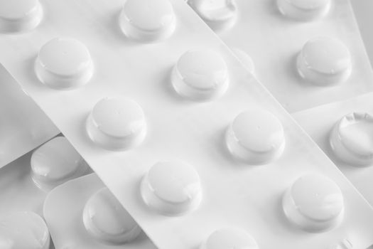 White pills in white blister on white background.