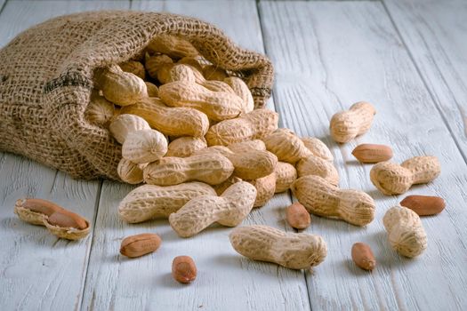 peanuts in a bag on a white wooden background.