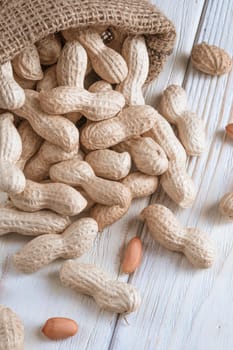 peanuts in a bag on a white wooden background.