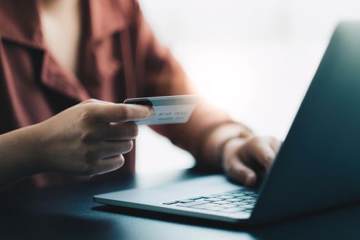 Hands holding plastic credit card and using laptop. Online shopping concept. Toned picture