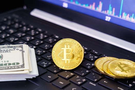 Bitcoins coin and banknotes on keyboard computer. Close up of  bitcoin crypto currency coins with trading exchange market price chart in the background