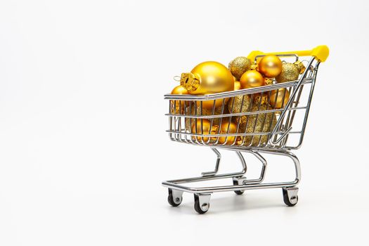Shopping trolley full of gold Christmas balls on the white background
