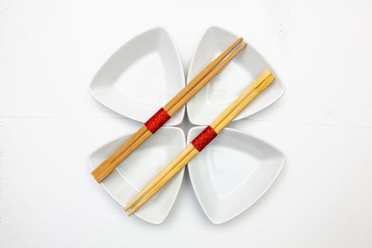 Ceramic bowls  and bamboo chopsticks for sushi food with red and white decoration.