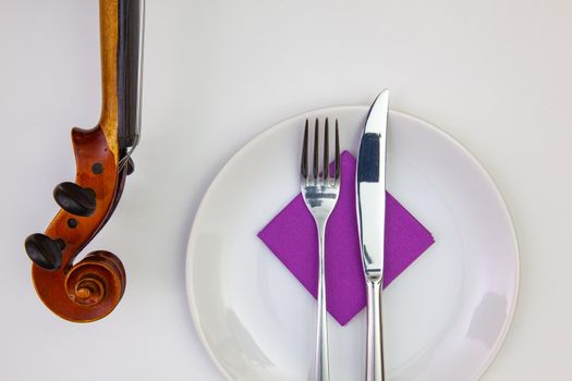 Symphony of taste. White plate and old violin on the white  wooden table.Top view. Flat Lay Image.
