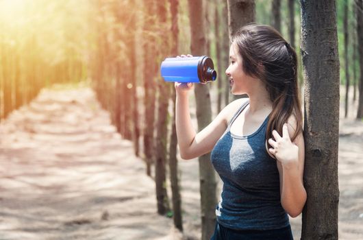Sport beautiful young woman girl lifestyle exercise healthy drinking water after running  workout in forest nature park with copy space