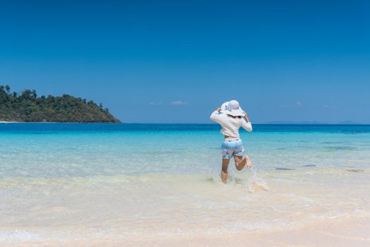 Happy young girl running to the beach at koh mook of Thailand