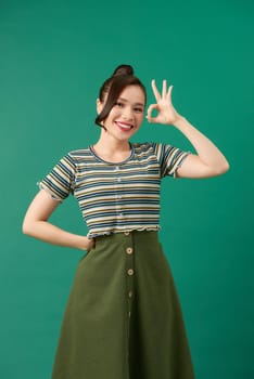 young happy smiling beautiful woman in casual clothing, showing okay gesture, or zero hand sign