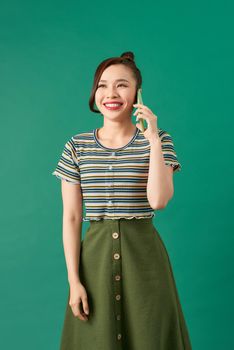 Cheerful Asian girl laughing while talking on cellphone,