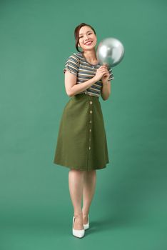 Beautiful young happy woman with smile, silver balloon on green background