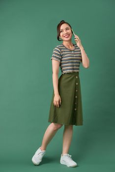 Full length portrait of a happy young woman talking on the phone isolated