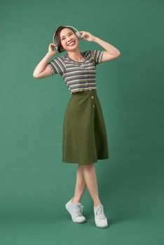 Music young girl dancing against isolated green background