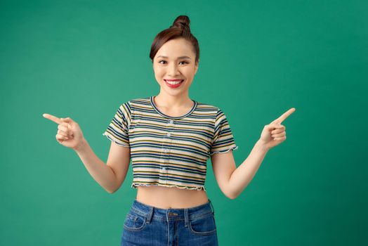 Pretty cheerful woman gesturing with fingers isolated over green background.