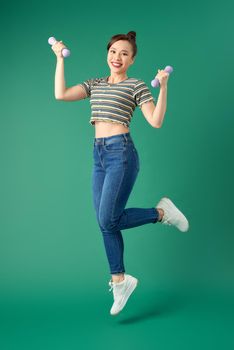 Young Asian woman in casual clothing with dumbell on green background.