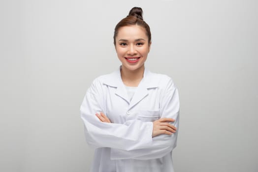 Young doctor woman wearing coat standing over isolated white background with a happy and cool smile on face.