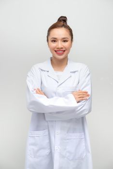 Smiling female doctor in lab coat with arms crossed against white background