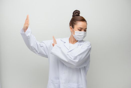 Young beautiful doctor woman wearing coat afraid and terrified with fear expression stop gesture with hands, shouting in shock.
