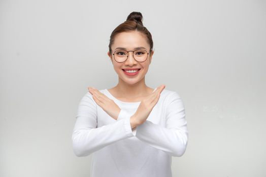 Portrait happy Asian beautiful young woman confident holding two crossing arms say no X sign on white background 