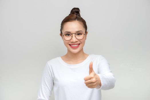 Portrait of a beautiful young asian woman showing thumbs up. Isolated on white background
