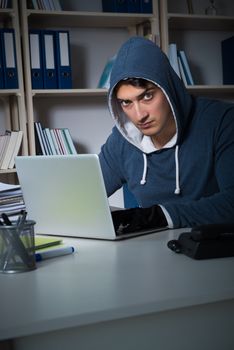 Young hacker hacking into computer at night
