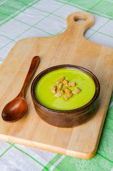 Spinach soup served on wooden board 