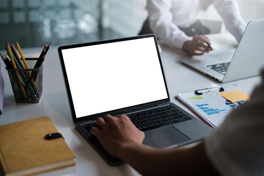 Laptop computer with blank screen on table with business people using keyboard