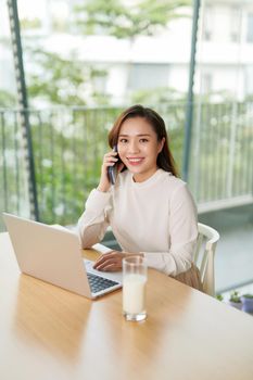 Photo of charming chinese businesswoman sitting at table and working with documents and laptop isolated