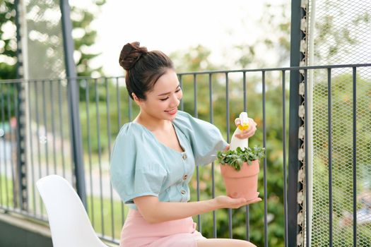 Woman is watering plants with water sprayer. Home gardening concept.