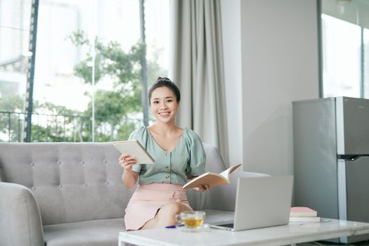 Photo of focused business woman hold pen sit sofa write notes fingers specs in home workstation indoors