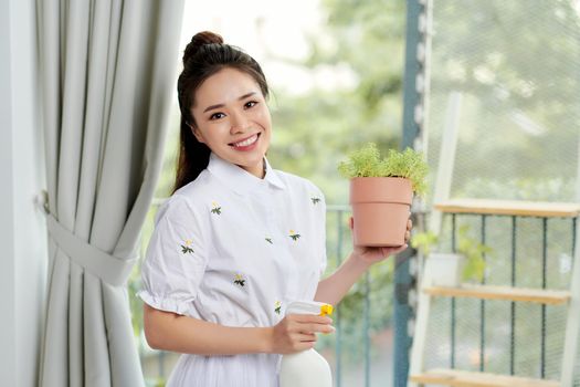 Young woman with potted plants on a garden balcony. Floriculture is a hobby. 