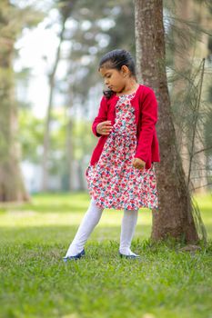 Little girl in flower dress and red sweater, very happy and smiling in the forest