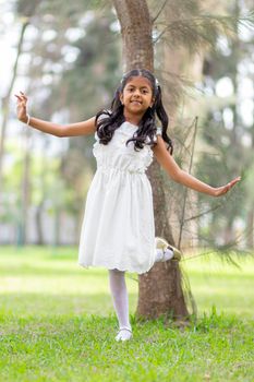 Little girl with white dress and red sweater, very happy and smiling in the forest
