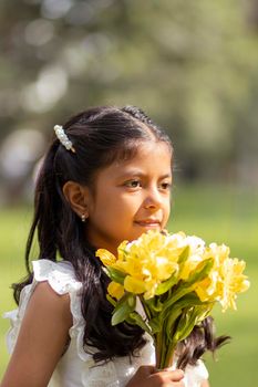 Little girl in white dress and with a cute bouquet of flowers in her hand